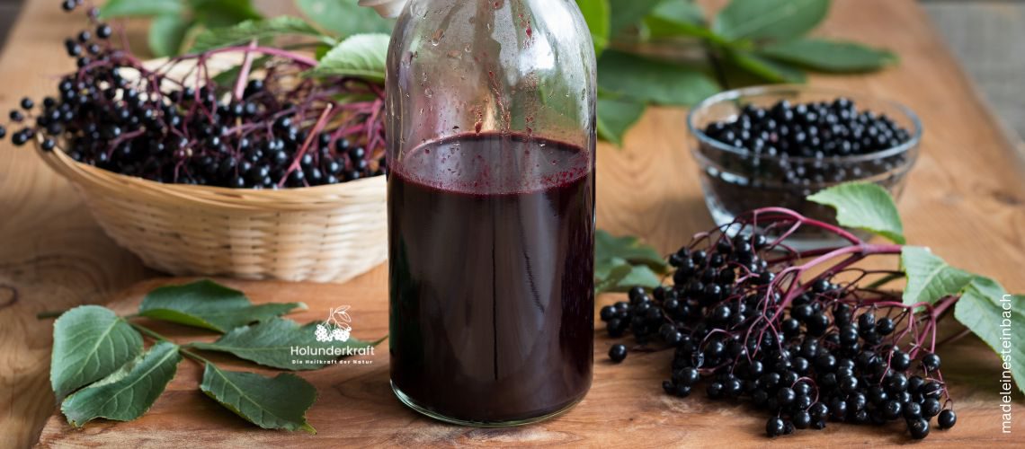 Flasche mit Holundersaft, Holunderbeeren und Blätter zum Thema wieviel Holundersaft darf man pro Tag trinken